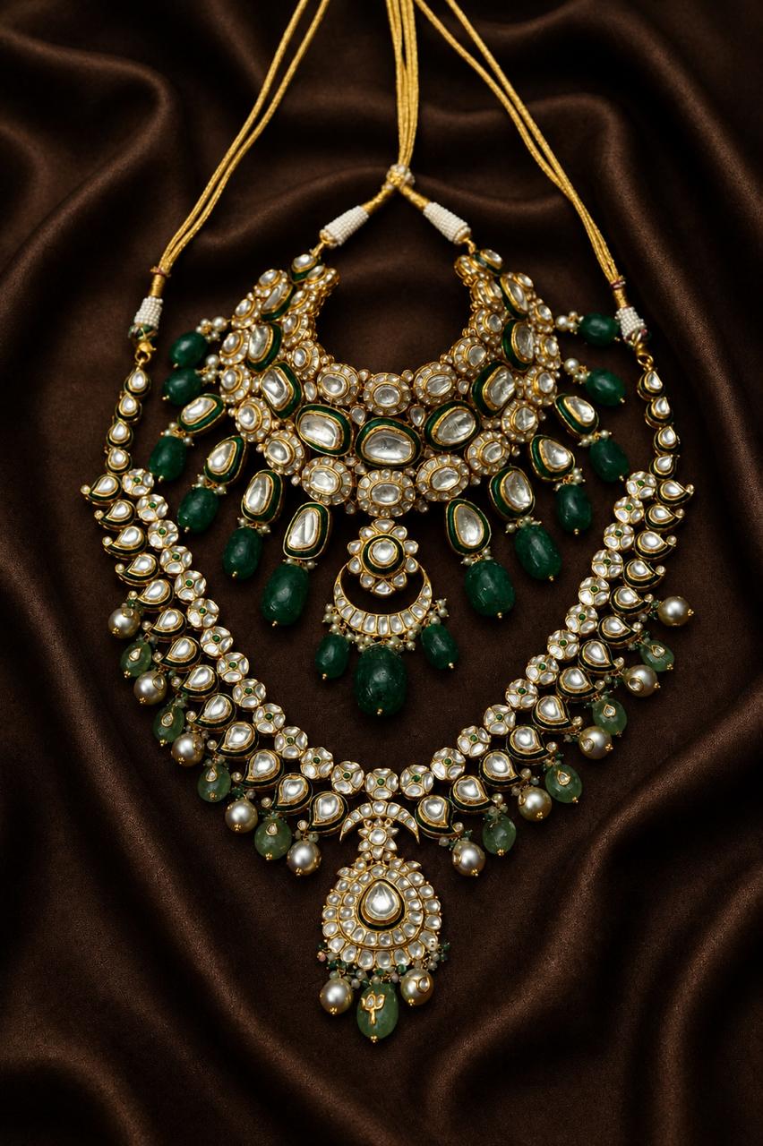 Gold kundan crescent necklace with emerald green stones and pearl drops on brown silk.